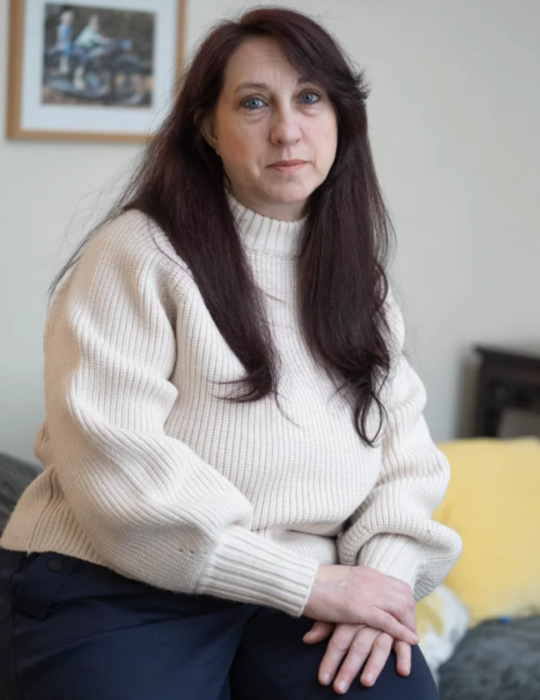 una mujer sentada viendo a la cámara lleva un suéter tejido color crema el cabello suelto lacio y largo