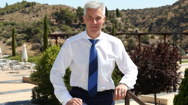 el ministro de defensa Artis Pabriks lleva una camisa blnaca y una corbata azul está en una casa de campo