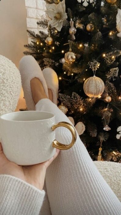 Mujer posando con taza de café y árbol de navidad
