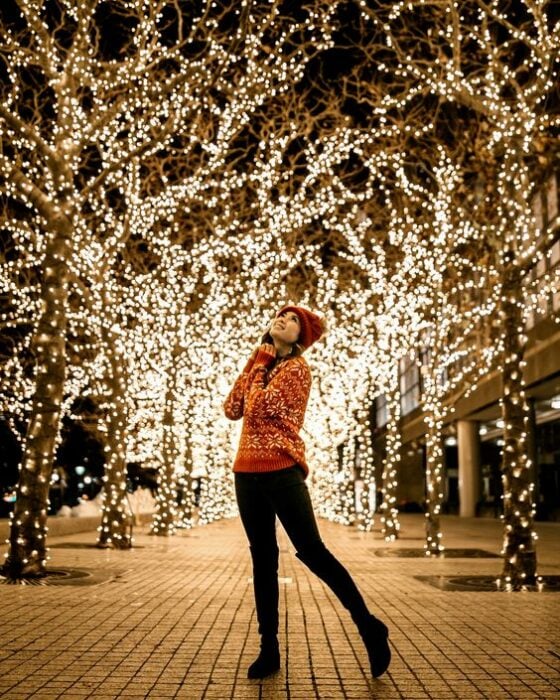 Mujer posando frente a luces navideñas