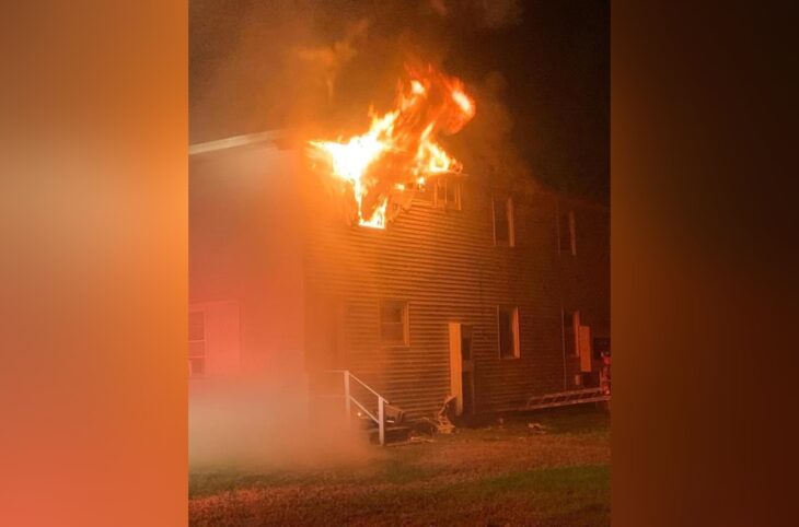 image of a house on fire two-story wooden structure with white facade