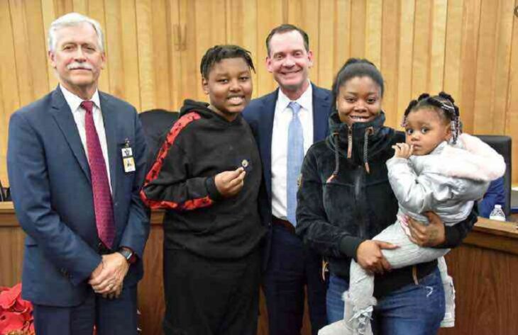 an 11-year-old boy receives an award for saving his little sister in a fire the people of the mayor's office give him an award 