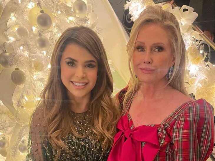 la cantante Paula Abdul junto a Kathy Hilton posando juntas cerca de un árbol decorado de Navidad ambas lucen vestidos de fiesta y maquillaje marcado