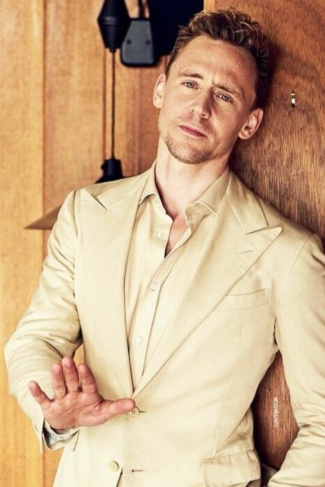 Tom Hiddleston posing in a cream dress suit
