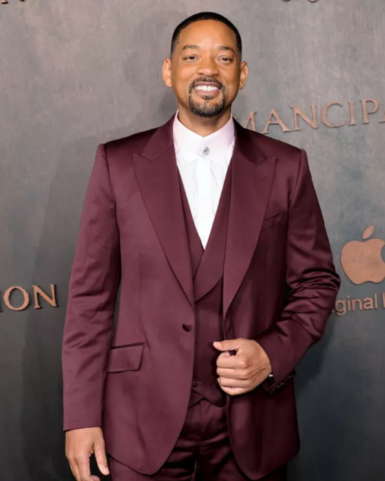 Will Smith posando en la alfombra roja de su nuevo filme Emancipación lleva un traje guinda sin corbata con una camisa blanca 
