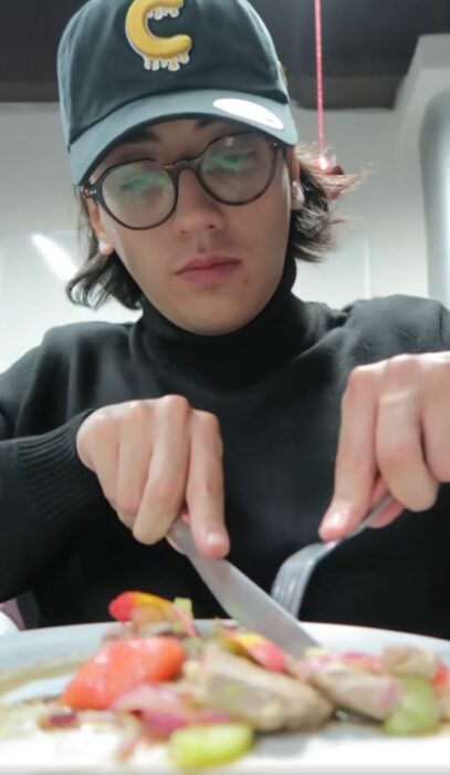 Hombre con gorra y lentes usando cubiertos para comer