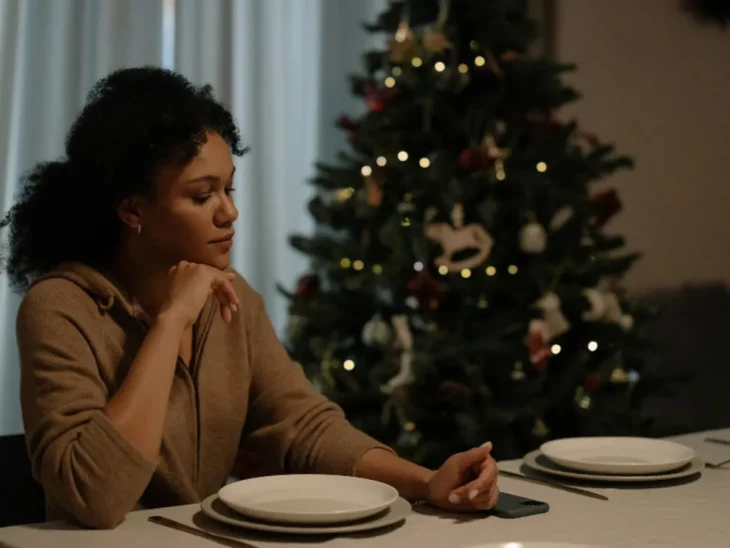 Mujer sentada a la mesa en navidad junto a silla vacía