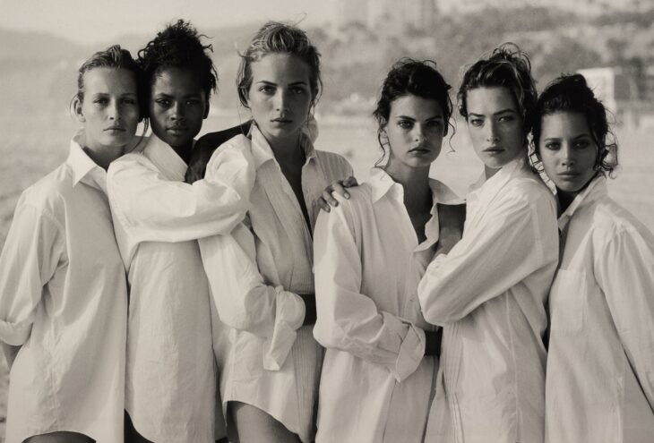 Tatjana Patitz, Estelle Lefébure, Karen Alexander, Rachel Williams, Linda Evangelista y Christy Turlington posando en la icónica foto tomada en una playa en 1988 por Lindbergh para Vogue titulada Camisas blancas: seis supermodelos Malibú