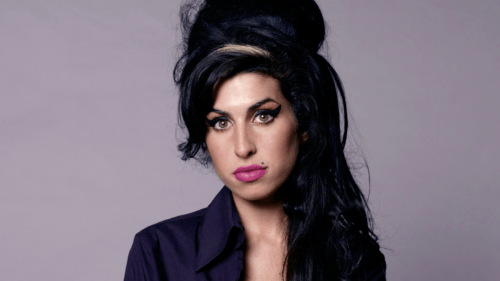 Amy Winehouse with her signature hairstyle wears a black top and makeup