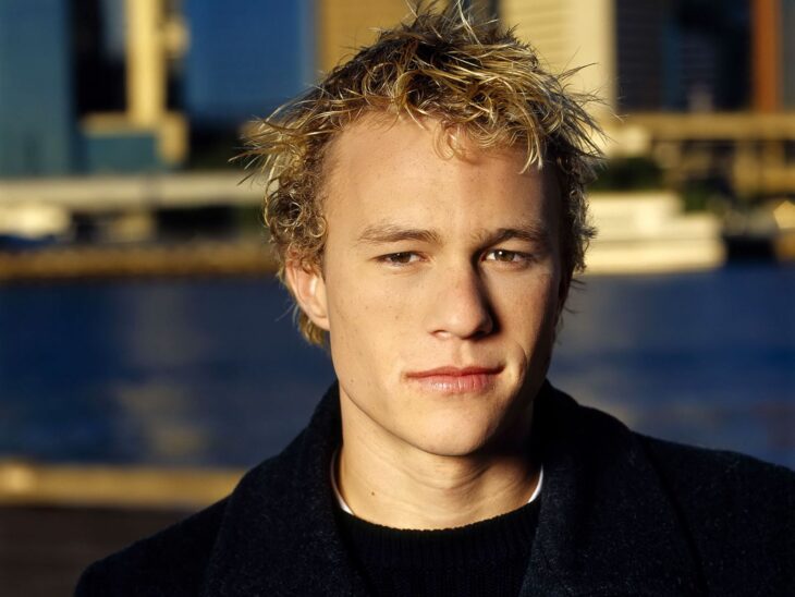 Heath Ledger poses in dark clothes in the back looks pretty water