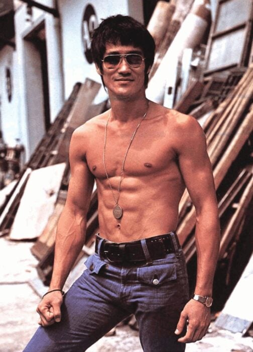 Bruce Lee on the set of a filming wears a bare torso and dark glasses