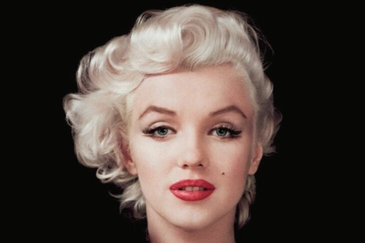 Marilyn Monroe's face wears heavy makeup and parted red lips