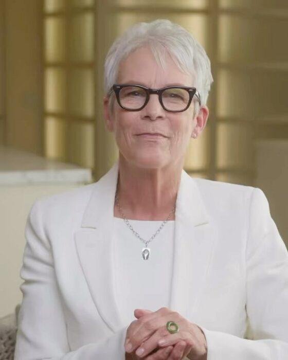 Jamie Lee Curtis sentada con traje sastre blanco 