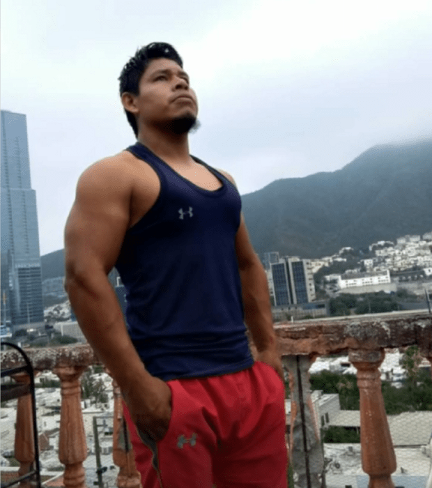 a man standing on a high balcony behind is seen the view of the city wears sportswear