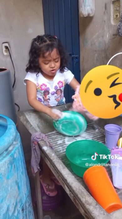 niña lavando trastes en un lavadero 