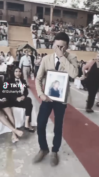 captura de pantalla de un video de TikTok que muestra a un joven con el retrato de su mamá en la entrega de su certificado