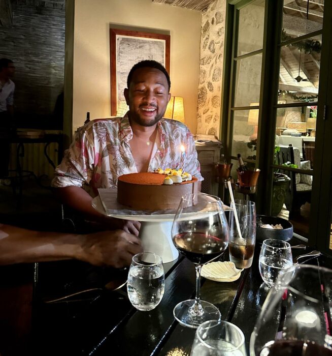 Cantante estadounidense John Legend frente a un pastel de cumpleaños en un restaurante 