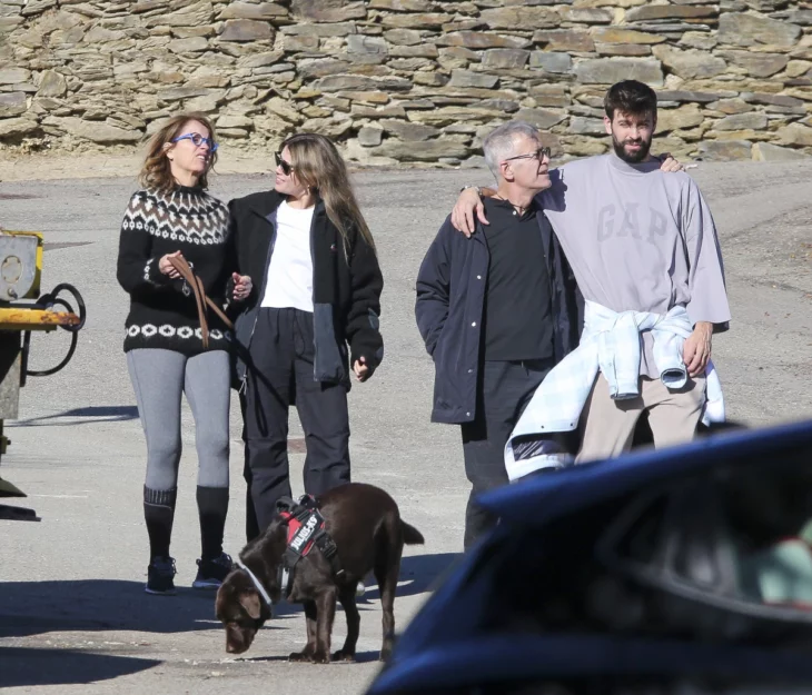 dos adultos mayores caminan por la playa con una pareja joven y un perro