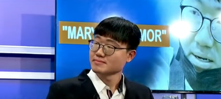 Seon Yong Lee a young South Korean in a television interview wears a black suit and white shirt brings magnifying glasses