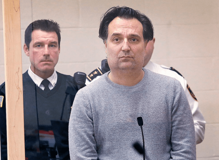 a man testifying in court behind him are two policemen