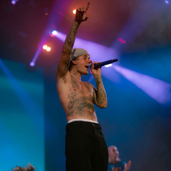 Photograph of Justin Bieber during a concert with his hand directed towards the public 