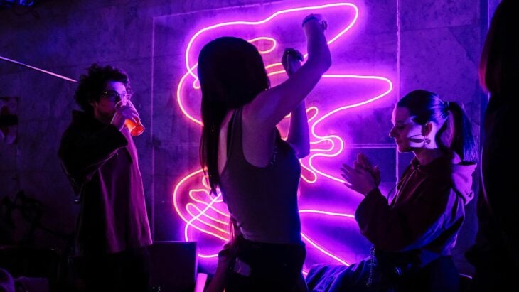 mujer bailando en un club nocturno rodeada de un par de personas 
