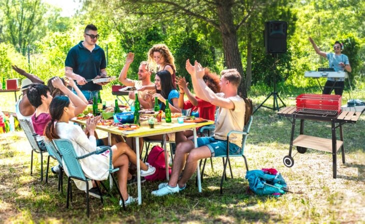 imagen que muestra a un grupo de personas comiendo al aire libre en un jardín 