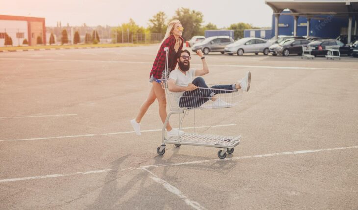 pareja jugando en un carrito en el estacionamiento de un supermercado 