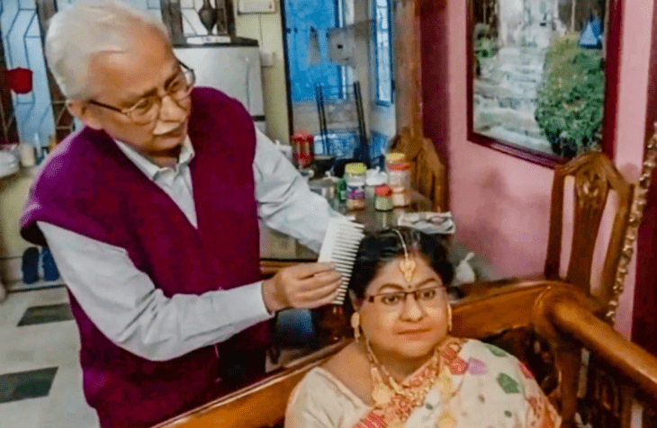 el viudo de una mujer de la India peina la figura de cera de su esposa fallecida por Covid la figura está vestida como se usa en la India y lleva vistosas joyas de oro como adorno el hombre porta un chaleco de color guinda y una camisa de manga larga gris lleva un peine en las manos y peina el cabello de la escultura