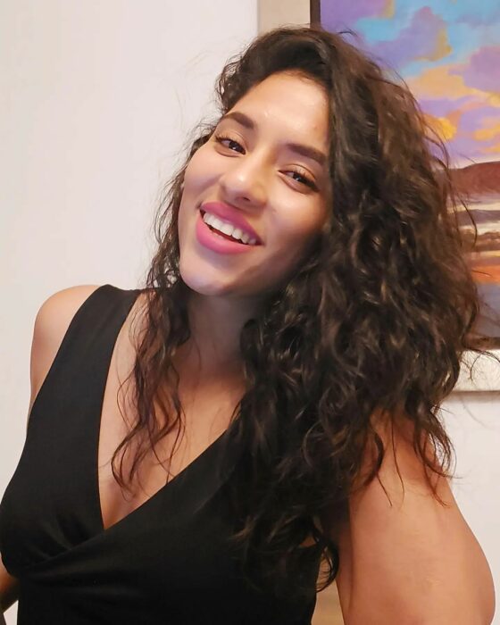 Smiling 34-year-old Peruvian influencer Marilyn Yesenia Martínez wearing a black v-neck blouse with her hair down 