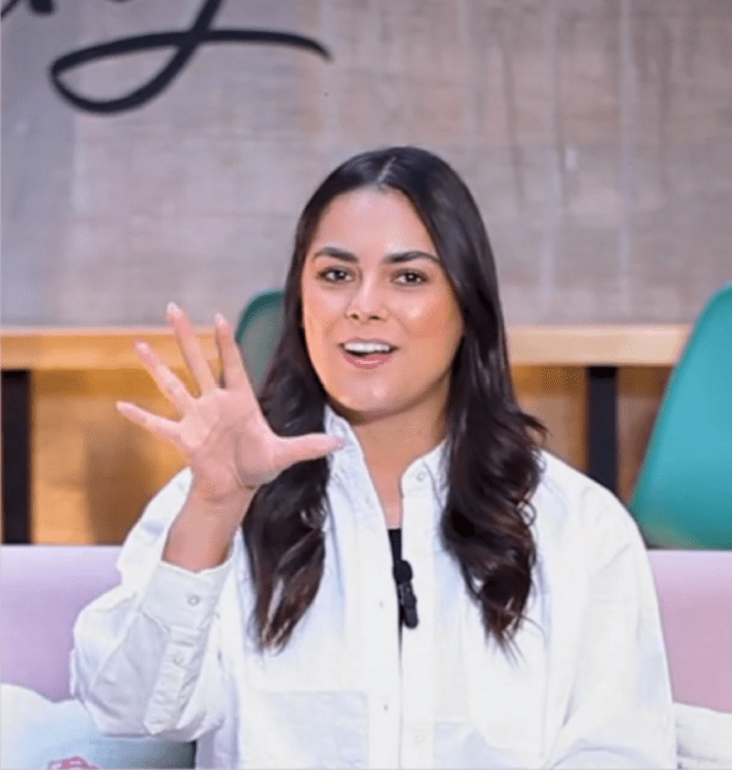 a girl in a white dress blouse speaks on a recording forum her hair is loose