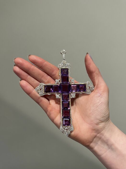 image of a hand holding the famous Attallah cross iconic jewel worn by Lady Di 