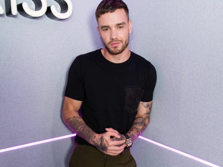 Liam Payne pictured in the corner of a room wearing dark clothing and tattoos on his arms