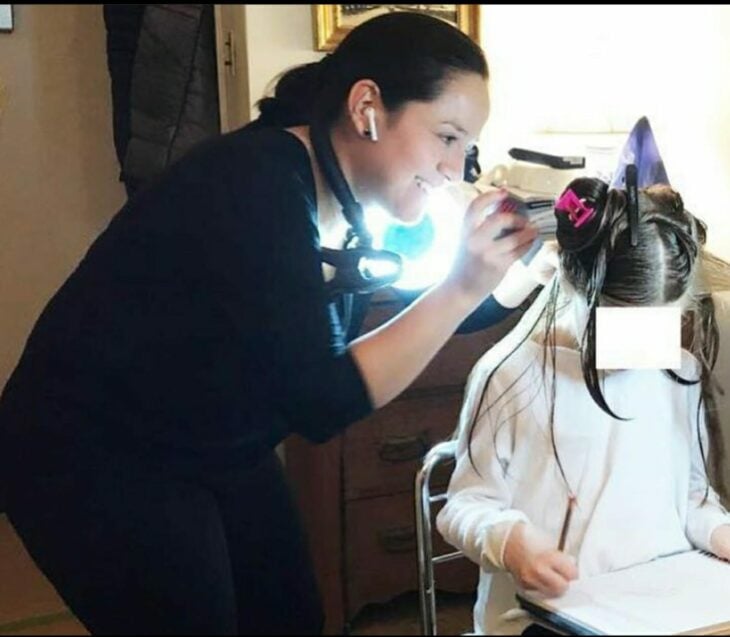 Woman removing head lice from a girl 