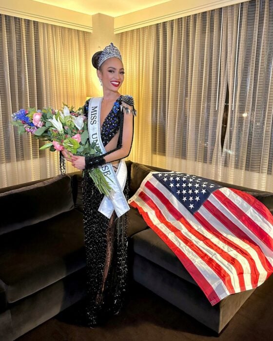 Fotografía que muestra a R'Bonney Nola Gabriel posando con su corona, unas flores y la bandera de Estados Unidos luego de ganar el certamen de Miss Universo 
