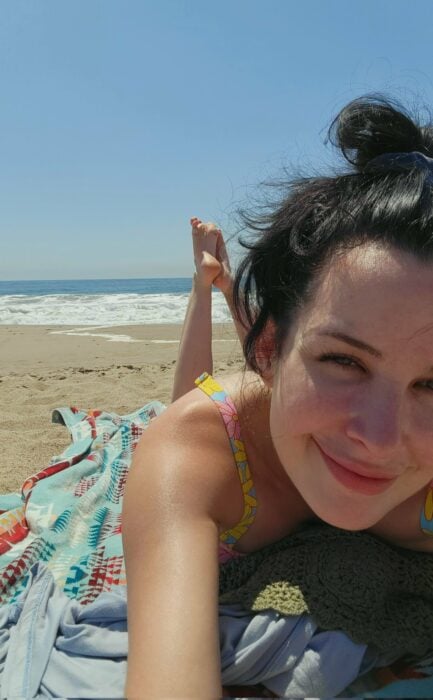selfie de una mujer acostada en la arena de una playa 