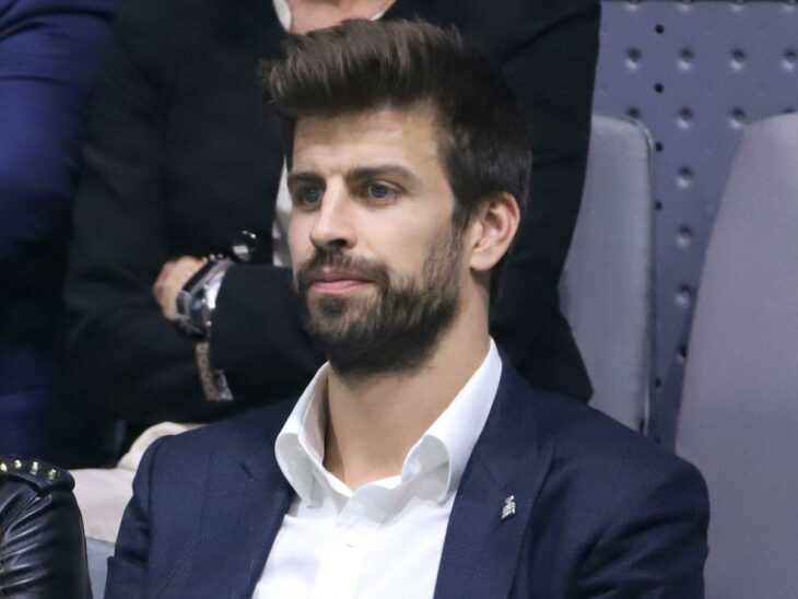 Gerard Piqué dressed in a navy blue suit and white shirt seated