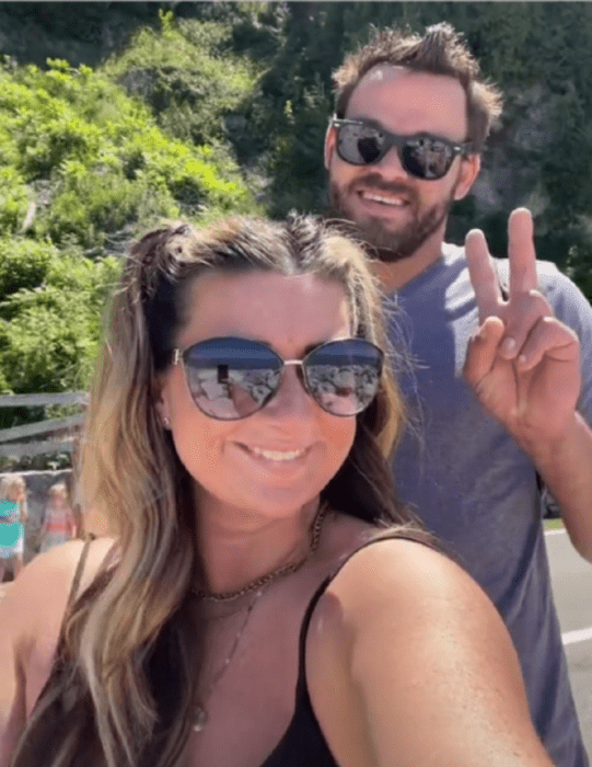 a couple taking a selfie they both wear sunglasses and casual clothes