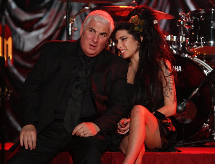 Amy Winehouse al lado de su papá Mitch sentados sobre el escenario de los Grammys