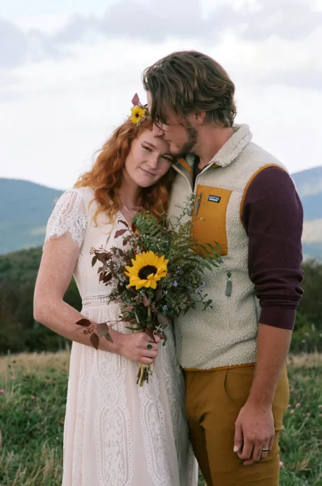 couple celebrating their wedding in the countryside wear casual clothes and a bouquet of wild flowers