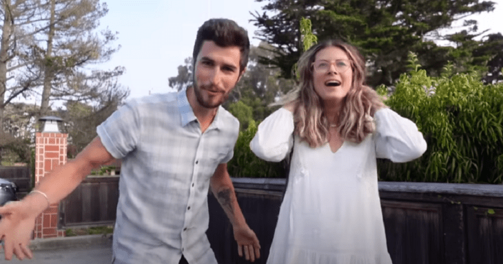 a caucasian couple smiles funny at the camera they are both wearing casual clothes