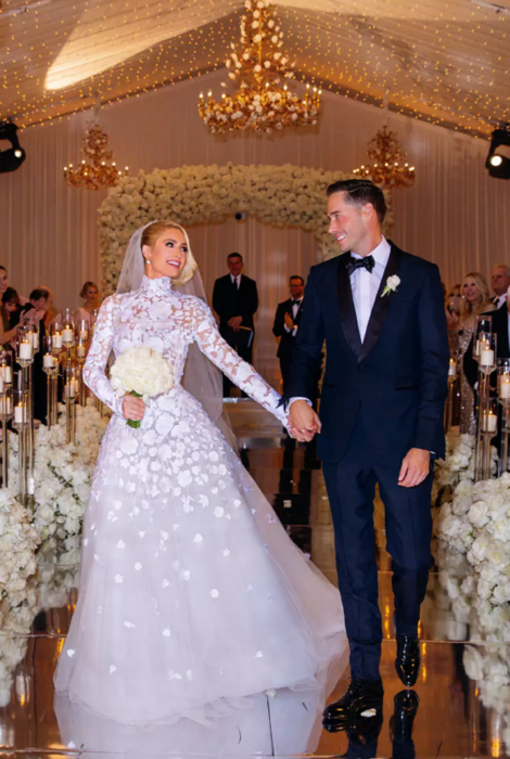 Paris Hilton y su esposo Carter Reum saliendo de su boda religiosa están vestidos de novios