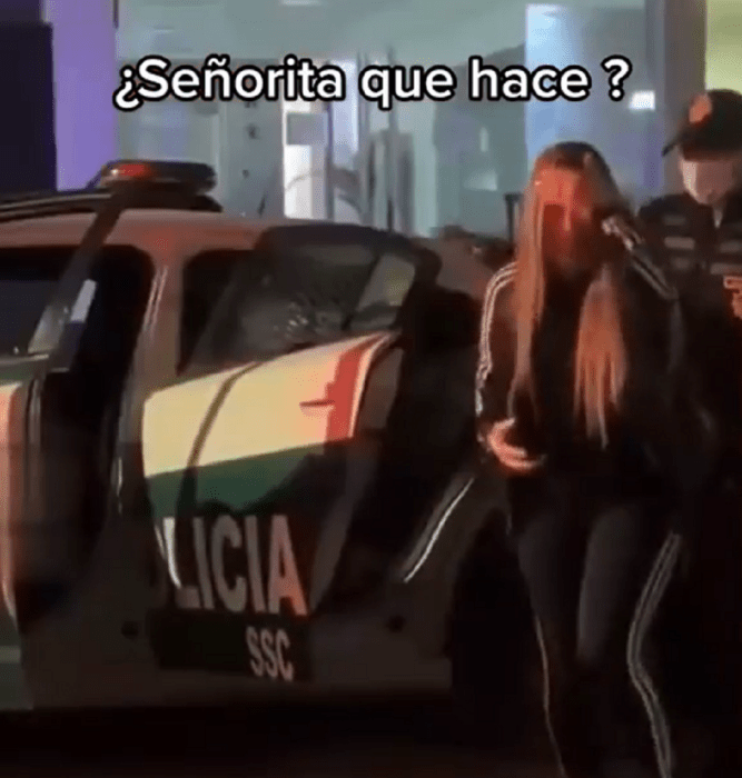 una mujer se apena al salir de la patrulla a la que se subió por error es de noche y trae su celular en la mano