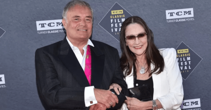 Leonard Whiting y Olivia Hussey en la alfombra roja de algún evento él lleva un saco negro con camisa blanca y ella una blusa negra con saco blanco y anteojos de sol