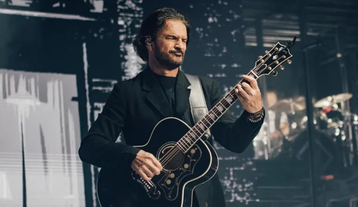 Ricardo Arjona en concierto en el escenario está vestido con ropa oscura