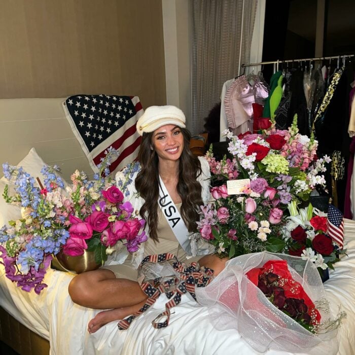 R´Bonney Gabriel sentada con flores y la banda de ISA en el camerino de Miss Universo