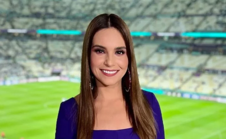 Tania Rincón en un estadio de futbol lleva vestido morado y el cabello suelto