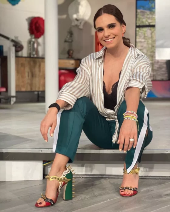 Tania Rincón sentada en un escalón con pose relajada lleva pantalón verde y blusa de rayas clara