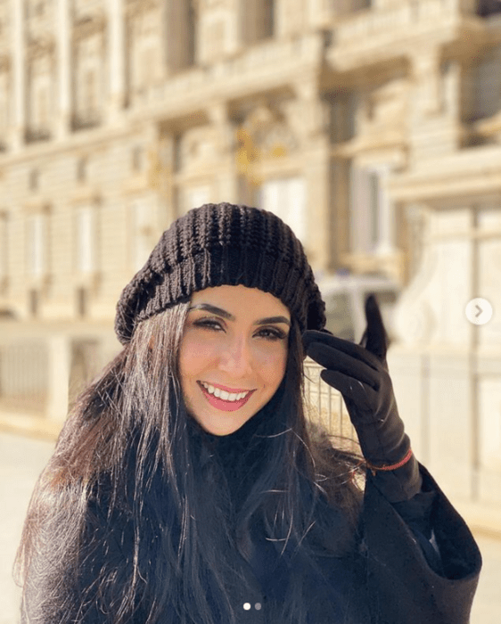 a woman dressed in dark winter clothes and hat with gloves 