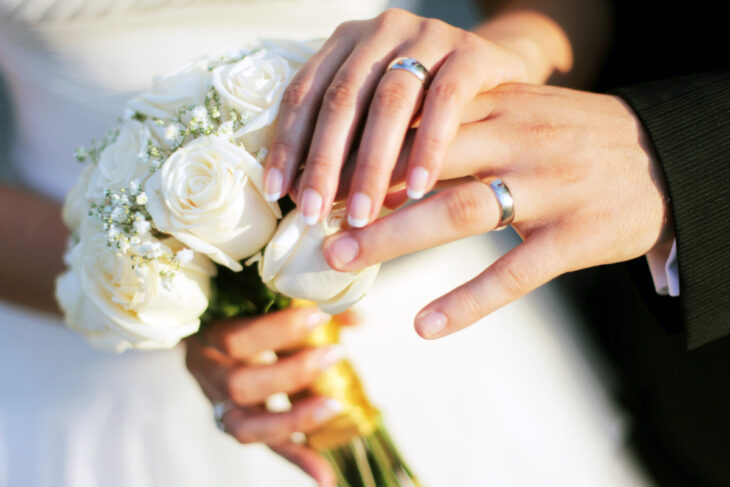 Manos de novios en boda usando anillos de matrimonio